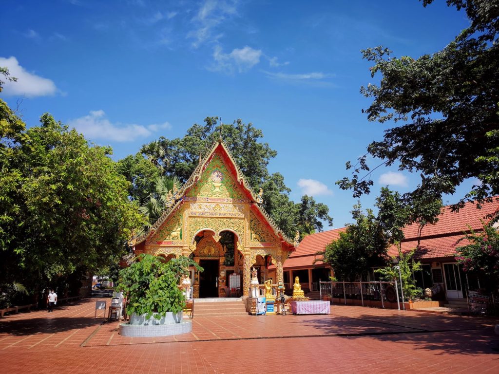 a buddhist temple near green trees under blue sky