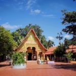 a buddhist temple near green trees under blue sky